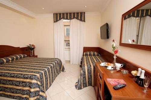 a hotel room with two beds and a table and a mirror at Guest House Galaxy in Rome