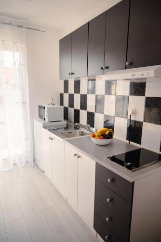 a kitchen with white cabinets and a bowl of fruit on a counter at Apartmani Natalija 4 Stars in Mrljane