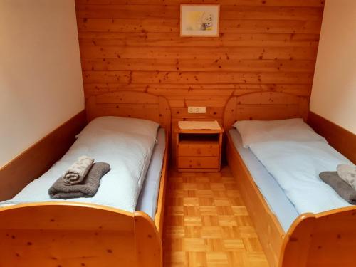 two beds in a room with wooden walls at Lärchenhof in Maria Alm am Steinernen Meer