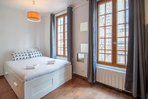 - une chambre avec un lit blanc et 2 fenêtres dans l'établissement Studio spacieux dans le beau quartier du Marais, à Paris