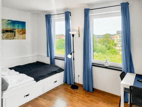 a bedroom with a bed with blue curtains and a window at Luna Port w Rowach in Rowy