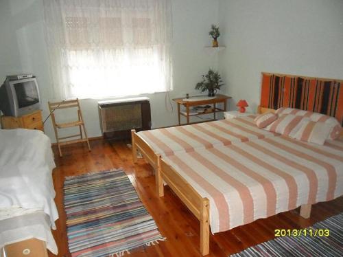 Muskátlis vendégház في Mátraderecske: غرفة نوم بسرير كبير وتلفزيون