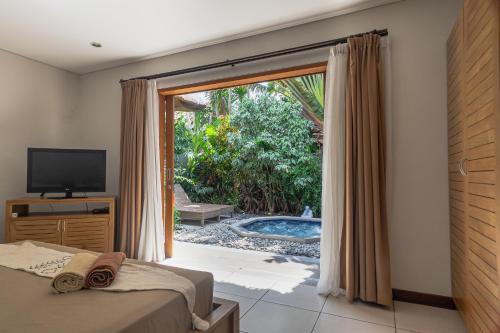 a bedroom with a sliding glass door to a swimming pool at Balinea Holiday Home in Kerobokan