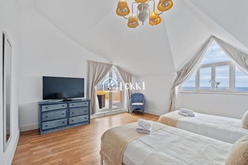 Una sala de estar con dos camas y un televisor. en Penthouse Paradise - Sotogrande, en Sotogrande