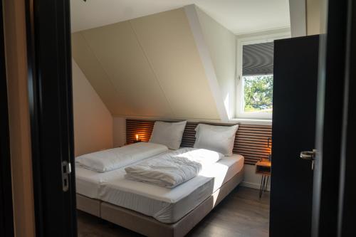 a bedroom with a bed with white sheets and a window at Waterdorp Burdaard in Burdaard