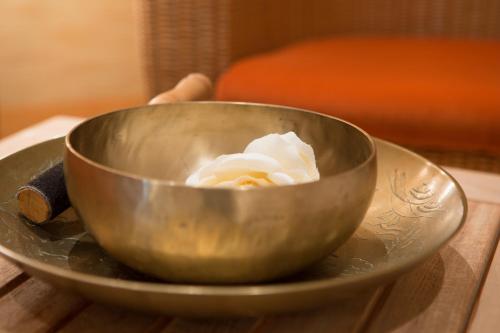 a metal bowl with a flower in it on a table at Hotel Pienzenau Am Schlosspark in Merano