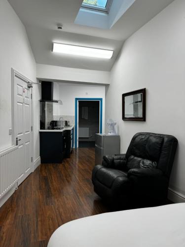 a living room with a black leather couch and a kitchen at Nikoda Lodge in Gillingham