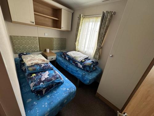 a small room with two beds and a window at Family 3 Bedroom Caravan at Heacham Beach in Hunstanton