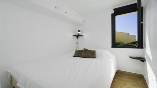 une chambre blanche avec un lit blanc et une fenêtre dans l'établissement TERRASSE DE LA PLAGE -211- Appt 4 pers, au Cap d'Agde