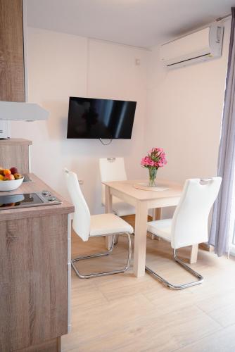 a kitchen with a table and two white chairs at Apartmani Natalija 4 Stars in Mrljane