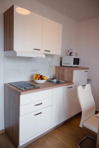 a kitchen with white cabinets and a bowl of fruit on the counter at Apartmani Natalija 4 Stars in Mrljane