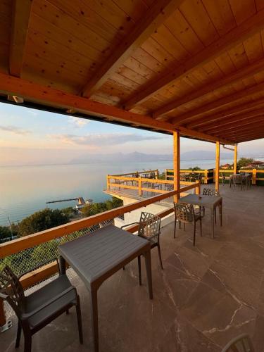 a patio with tables and chairs and a view of the ocean at Bujtina e Qilimave in Zogaji