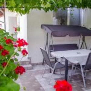 a patio with a table and red flowers at Guesthouse Juli in Sapareva Banya