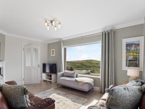 a living room with a couch and a window at Mourneen Cottage, Cleggan in Cleggan