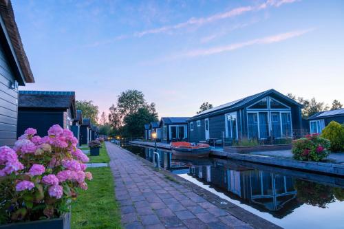 a group of houses on a canal with a boat at Waterpark Giethoorn in Giethoorn