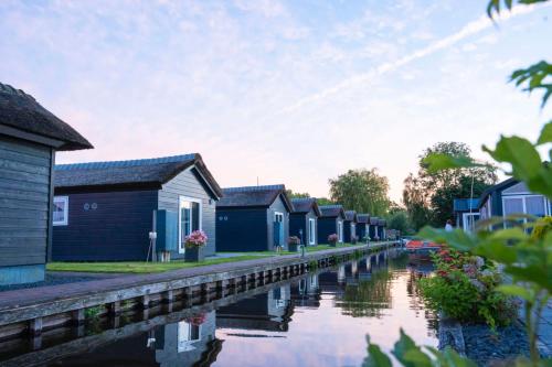 eine Reihe bunter Häuser neben einem Kanal in der Unterkunft Waterpark Giethoorn in Giethoorn
