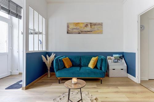 a living room with a blue couch and a table at L'Étape de la Porte - Appt niché au cœur Mouzon in Mouzon