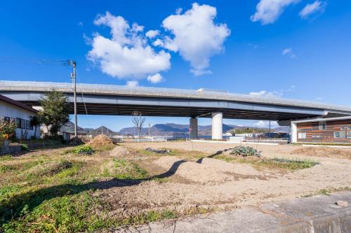 a bridge over a road with a dirt field at 農家民宿河西園 in Takamatsu