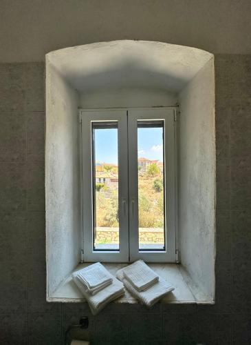 a window in a bathroom with four towels on a window sill at Chrysavgi Stone House in Meganisi