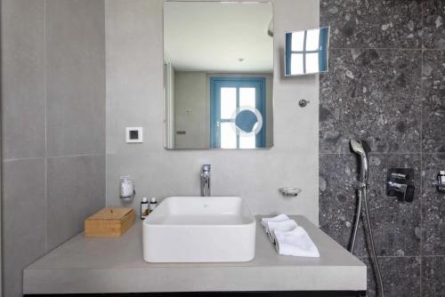 a bathroom with a white sink and a mirror at Aeifos Boutique Hotel in Imerovigli