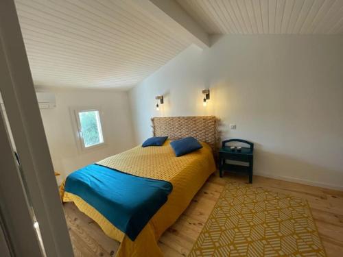 - une chambre dotée d'un lit avec une couverture bleue et jaune dans l'établissement Les planètes du port, à Marseillan