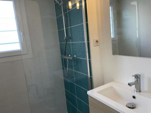 une salle de bain avec une douche, un lavabo et un miroir dans l'établissement Les planètes du port, à Marseillan