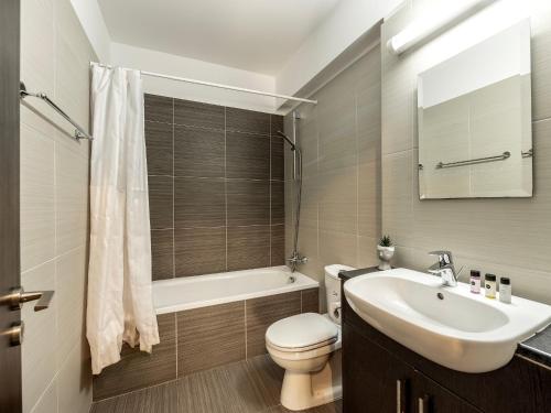 een badkamer met een wastafel, een toilet en een bad bij Mythical Sands Resort in Protaras