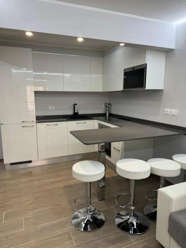 une cuisine avec des armoires blanches et un comptoir avec des tabourets dans l'établissement Appartamento Esclusivo in Monaco Palace Josephine, à Beausoleil