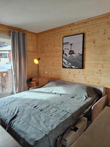- une chambre avec un grand lit dans un mur en bois dans l'établissement Superbe appartement rénové, à Allos