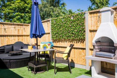 a patio with a table and an umbrella and a grill at Farm Elegance at Lottie's Lodge in Hutton