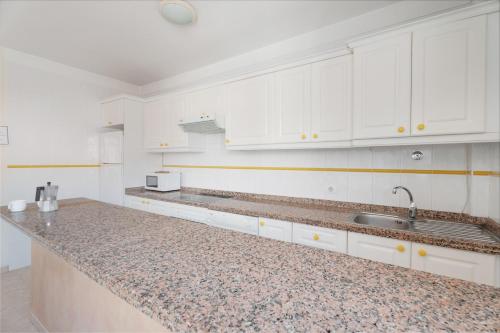 a kitchen with white cabinets and a granite counter top at Isla 1 in San Isidro