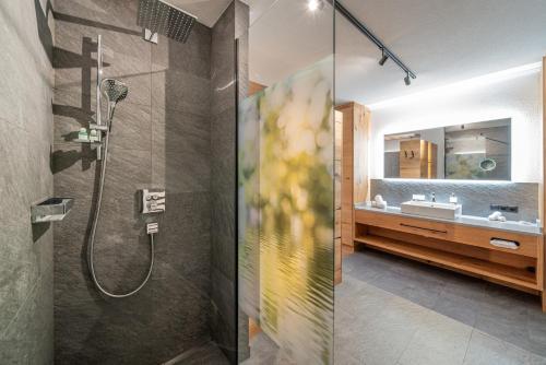 une salle de bain avec douche et lavabo dans l'établissement Hotel Mittagskogel Pitztal, à Sankt Leonhard im Pitztal