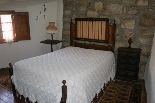 a bedroom with a bed and a stone wall at Casa Campo Das Bizarras in Castro Daire