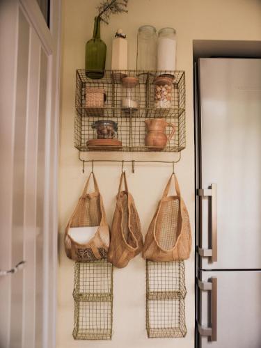 une cuisine avec des paniers sur le mur à côté d'un réfrigérateur dans l'établissement Villa Echynops, derrière les dunes, à Lacanau