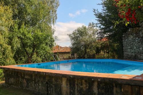 a swimming pool in a yard with a stone wall and trees at Casa Campo Das Bizarras in Castro Daire