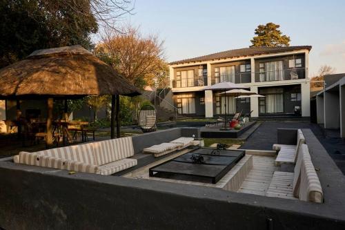 a house with a patio with couches and an umbrella at Cosy apt 5min to Sandton City 14 in Johannesburg