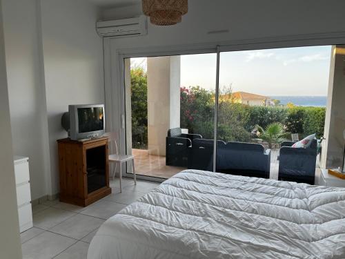 - une chambre avec un lit, une télévision et un balcon dans l'établissement Appartement avec jardin vue mer, à Lumio