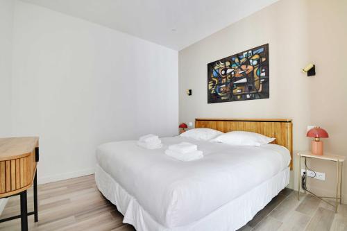 une chambre avec un grand lit blanc et un bureau dans l'établissement Charming apt with patio - 2BD4P - Monceau Park, à Paris
