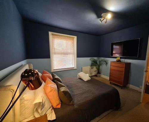a blue bedroom with a bed and a television at Beach Hideaway in Shanklin