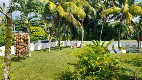 a resort yard with palm trees and a fence at Maison Amantine in Mahe