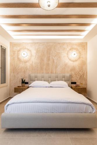 a bedroom with a large white bed and a wooden ceiling at Perla Hotel in Agios Prokopios