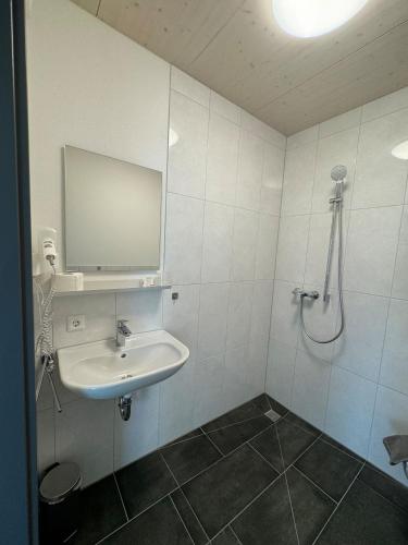 a white bathroom with a sink and a shower at Hotel Lijo, bei Basel in Steinen