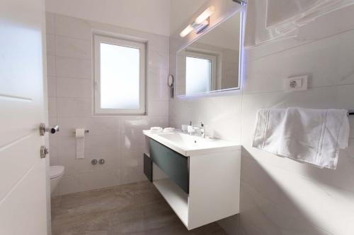 a white bathroom with a sink and a mirror at Villa Adrimar in Risika