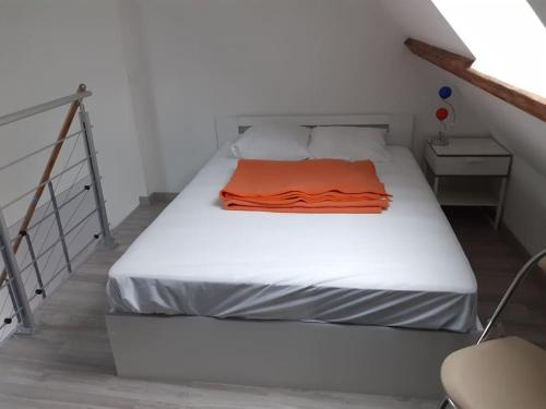 - un lit avec une couverture orange dans l'établissement Gîte des Vergers 