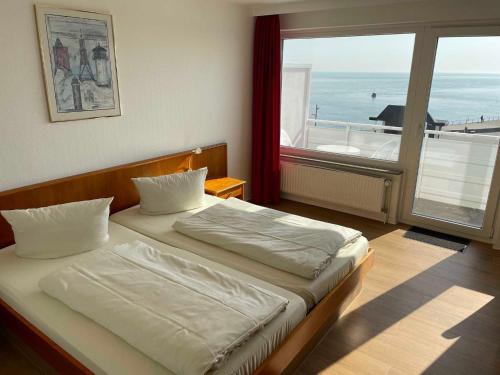 a bedroom with a bed and a large window at Seehotel in Helgoland