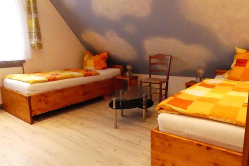 a bedroom with two beds and a table and a chair at An der Unstrutquelle in Kefferhausen