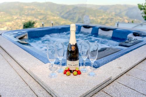 a bottle of champagne and wine glasses in a swimming pool at Paradise Farm with pool and jacuzzi in Douro in Santa Cruz do Douro