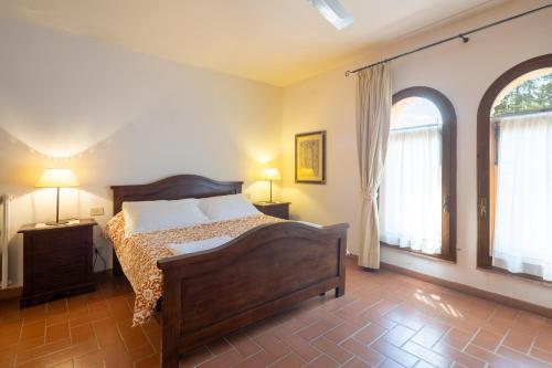a bedroom with a bed and two windows at Foresteria Castello di Verrazzano in Greve in Chianti