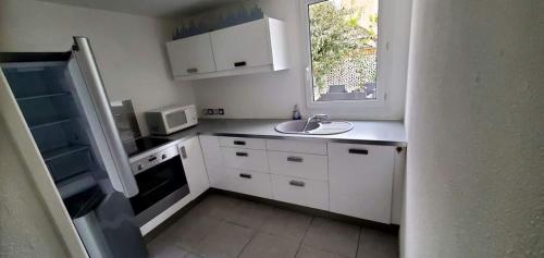 une cuisine blanche avec un évier et une fenêtre dans l'établissement Clos Gabmy entre plage et garrigue, à Vic-la-Gardiole