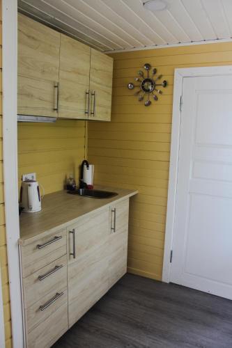 a kitchen with wooden cabinets and a white door at Lubānas Mototrase in Lubāna
